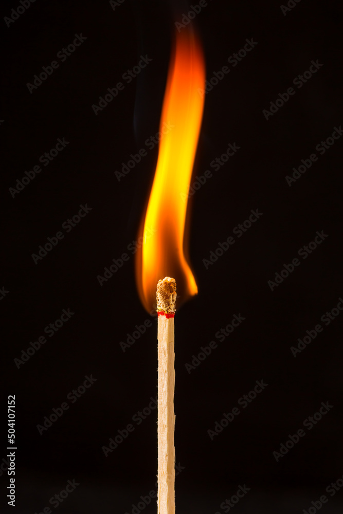 Burning matchstick on black background