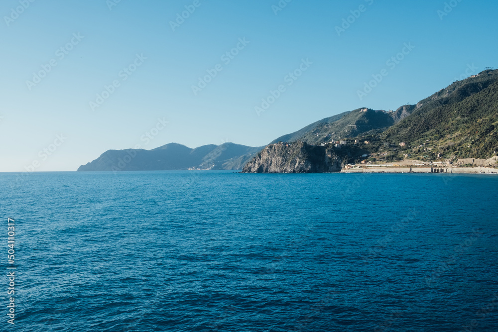 Beautiful seascape with blue sky, smooth water surface and rocky cliffs in Liguria coastal area. Popular italian travel destination.