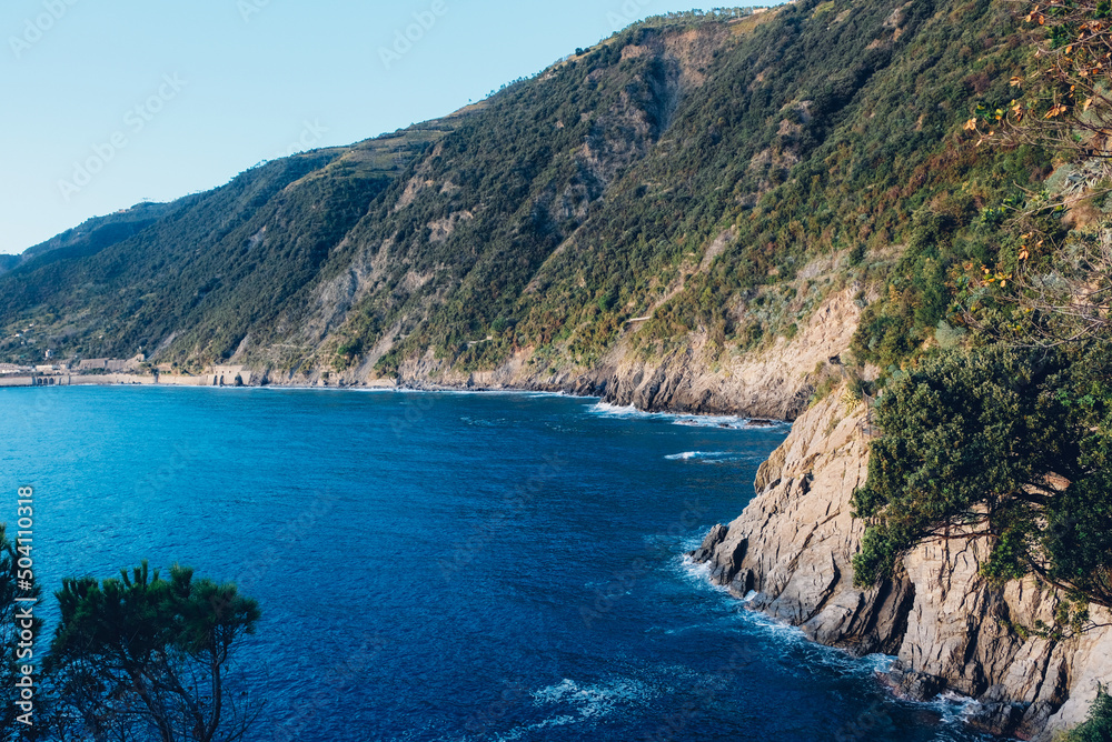 Fototapeta premium Beautiful seascape with blue sky, smooth water surface and rocky cliffs in Liguria coastal area. Popular italian travel destination.