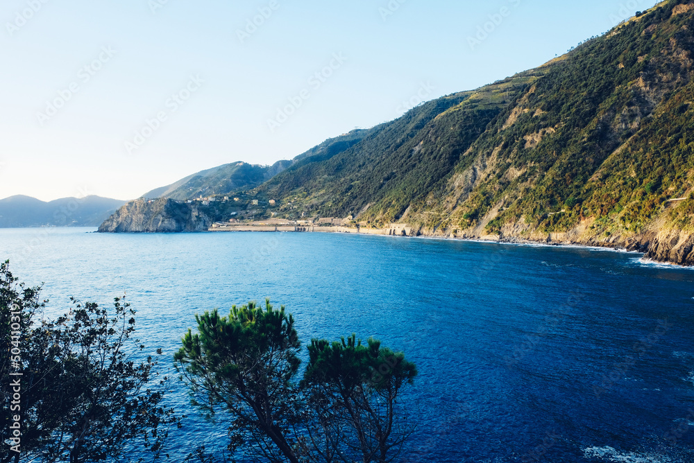 Beautiful seascape with blue sky, smooth water surface and rocky cliffs in Liguria coastal area. Popular italian travel destination.
