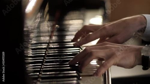 Male hands playing grand piano. Man touches fingers on keys. Professional pianist plays two hands classical music on a beautiful grand piano on stage in concert. Close up. 