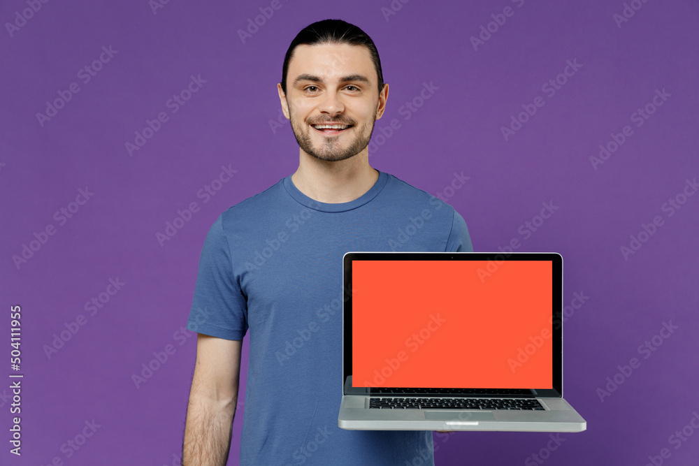 Young happy man 20s wearing basic blue t-shirt hold use work on laptop pc computer with blank screen workspace area browsing internet chatting online isolated on plain purple color background studio. Young happy man 20s wearing basic blue t-shirt hold use work on laptop pc computer with blank screen workspace area browsing internet chatting online isolated on plain purple color background studio.