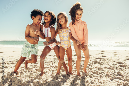 Photography Multiethnic kids playing together on beach sand