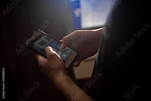 A man types a password on his smartphone. Dark background.