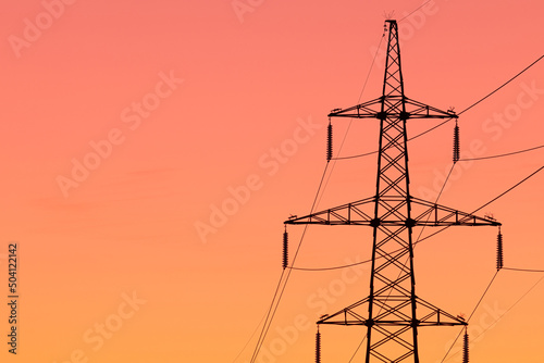 Background, view or scene of steel tower of electric main or electricity transmission line with the wires silhouette on yellow, orange and red background of sunset or sunrise sky
