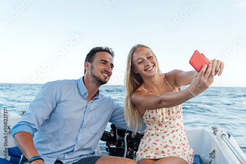 Young couple happily taking a selfie on a boat at sea. Enjoying the summer © Marc