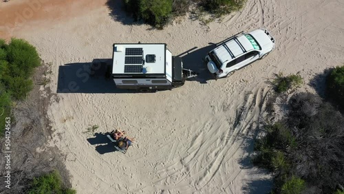 Australian couple relaxing during a beach holiday with 4WD vehicle and caravan on a sand dune in Western Australia outback. photo