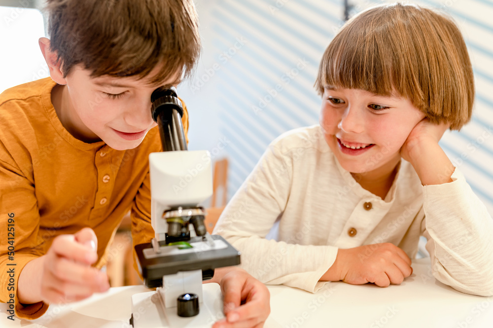 Young children looking through the microscope doing science project in school . STEM in education concept. Young children looking through the microscope doing science project in school . STEM in education concept.