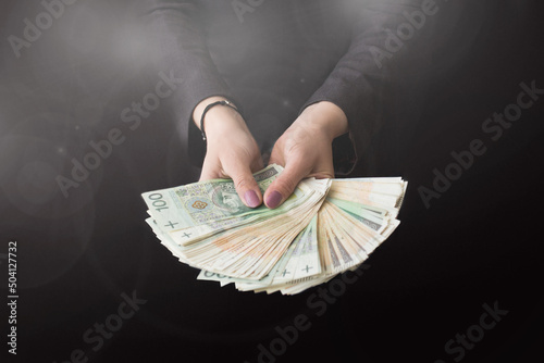 Kobieta wyciąga przed siebie ręce pełne pieniędzy, dużo pieniędzy w dłoni photo
