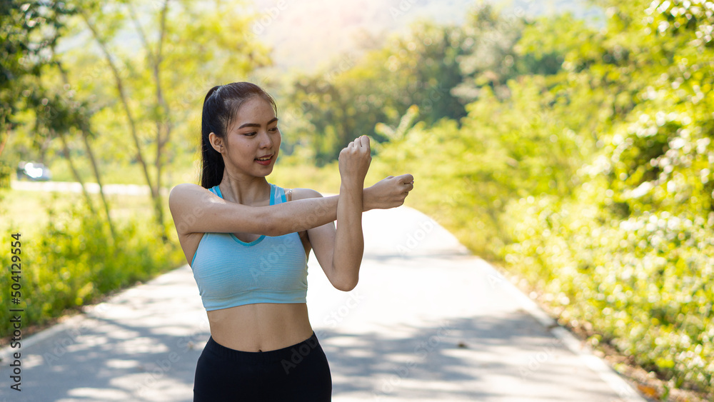 Asian women stretch before exercising for good health. Horizontal image while stretching in an outdoor park. A female runner warms up for an evening run and jogging. Asian women stretch before exercising for good health. Horizontal image while stretching in an outdoor park. A female runner warms up for an evening run and jogging.