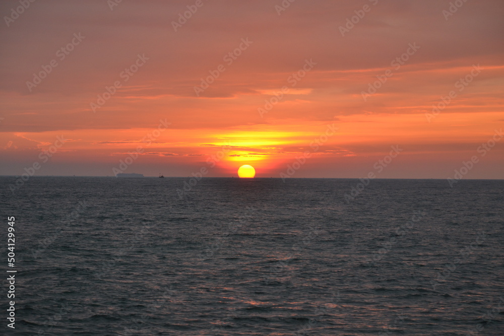 An orange-pink sunset over the water.