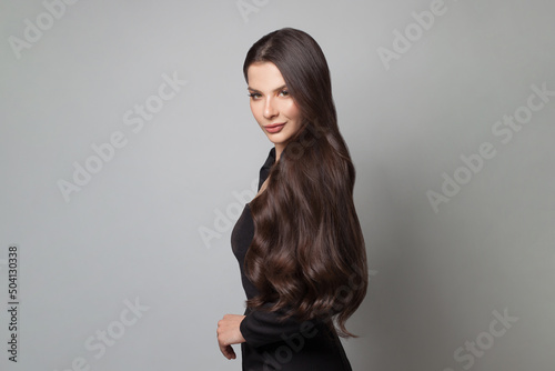 Brunette woman with long shiny dark curly hair. Beautiful model woman with wavy hairstyle. Care and beauty concept