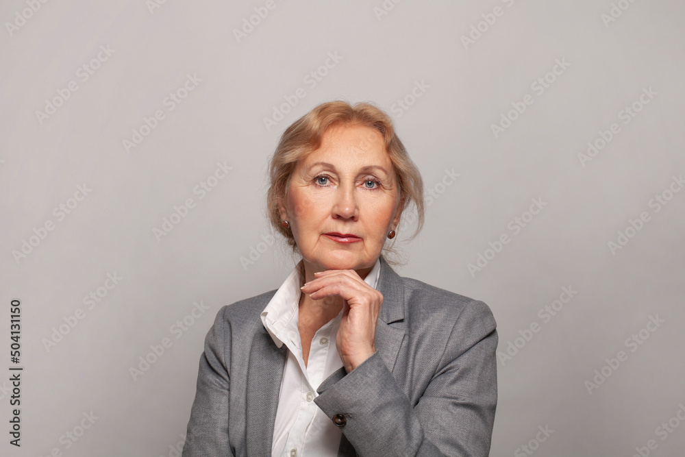 Beautiful senior lady smiling and looking at camera on gray background. Mature woman 60s portrait Beautiful senior lady smiling and looking at camera on gray background. Mature woman 60s portrait