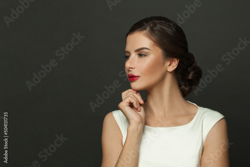 Beautiful female model profile. Brunette face with red lips makeup on black background