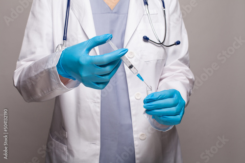 Medical worker hands in blue medical gloves dials the vaccine into a syringe close up