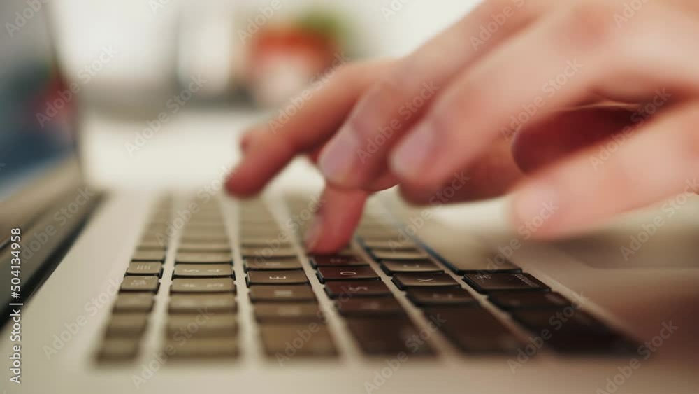 Close up of a person's hands typing on a laptop keyboard, indoors. Close up of a person's hands typing on a laptop keyboard, indoors.