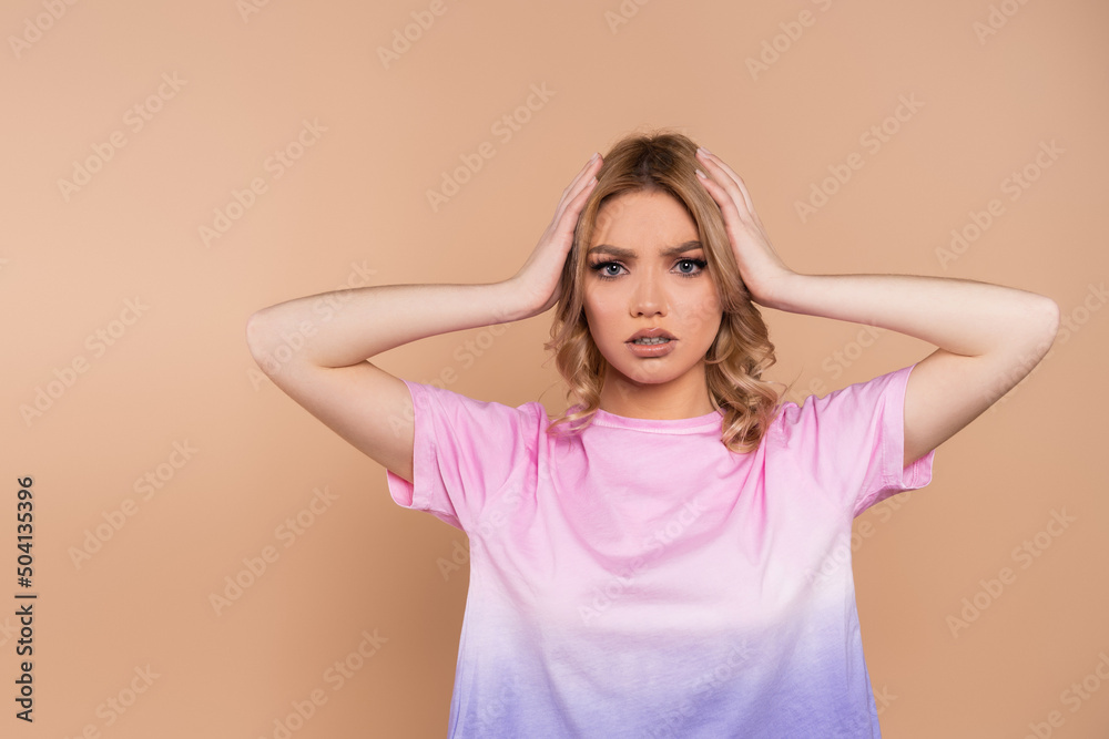 worried woman touching head and looking at camera isolated on beige. worried woman touching head and looking at camera isolated on beige.