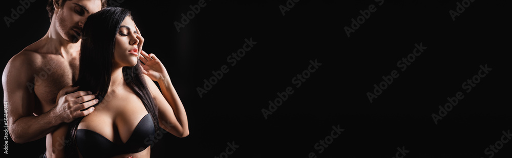 Shirtless man touching hair of sensual girlfriend in bra isolated on black, banner. Shirtless man touching hair of sensual girlfriend in bra isolated on black, banner.