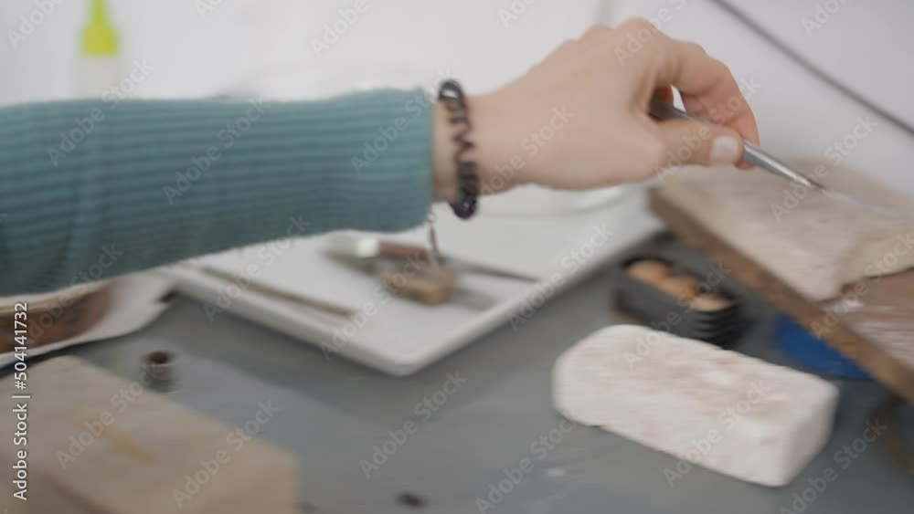 Female Jeweler Holding A Small Piece Of Metal With Tweezer. Close Up Female Jeweler Holding A Small Piece Of Metal With Tweezer. Close Up