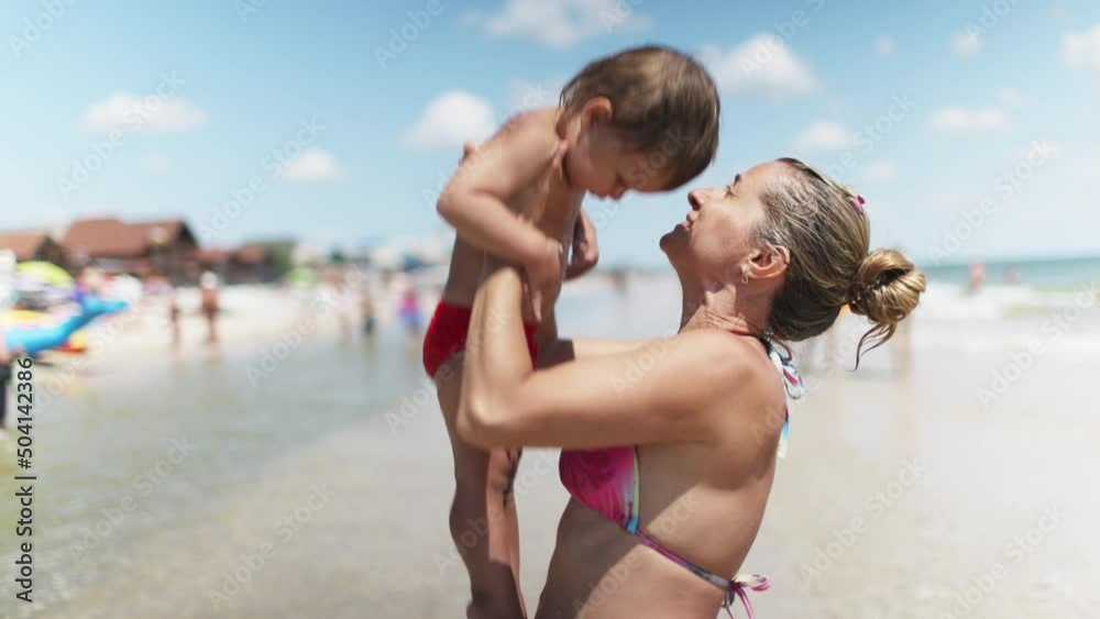 Mom throws her son up over the sea on summer vacation under the warm sun Mom throws her son up over the sea on summer vacation under the warm sun
