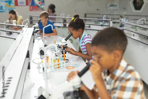 Multiracial elementary students using microscope during science practical in laboratory