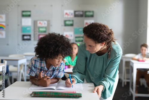 Foto Caucasian young female teacher assisting african american elementary schoolboy s