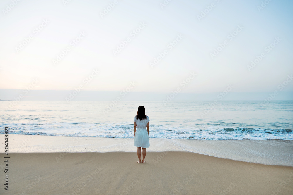 Young asian woman relaxing on the beach at sunrise. Young asian woman relaxing on the beach at sunrise.