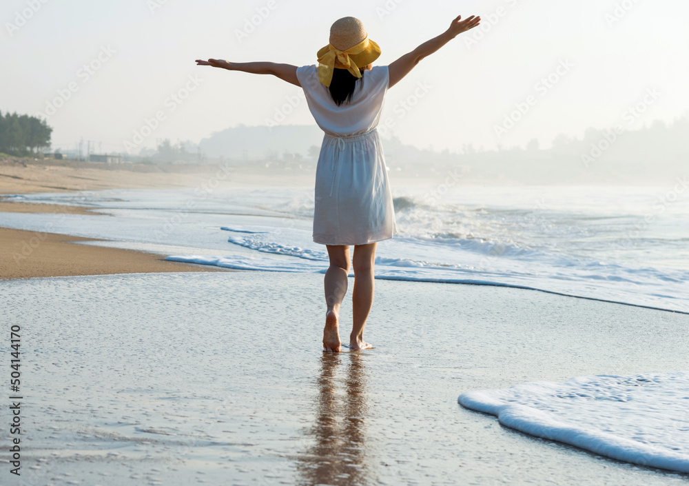 Happy woman standing on the beach with hands up. Stock Photo | Adobe Stock