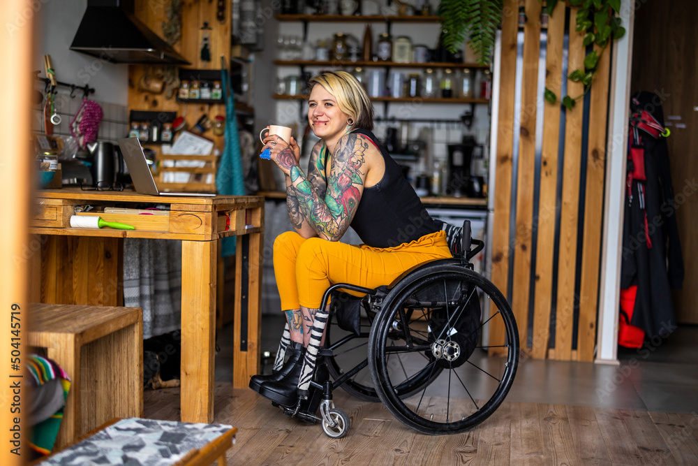 Obraz premium Portrait of an young tattooed woman in a wheelchair at home 