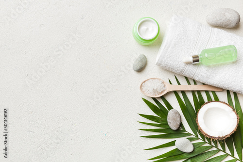 Coconut with jars of coconut oil and cosmetic cream on colored background. Top view. Free space for your text. Natural spa coconut cosmetics and organic treatment concept Coconut Spa composition