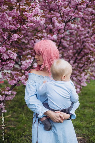 woman and son in nature playing at spring park. Little boy and mother have a good time on weekend activity in the blooming Sakura gardens © Marharyta