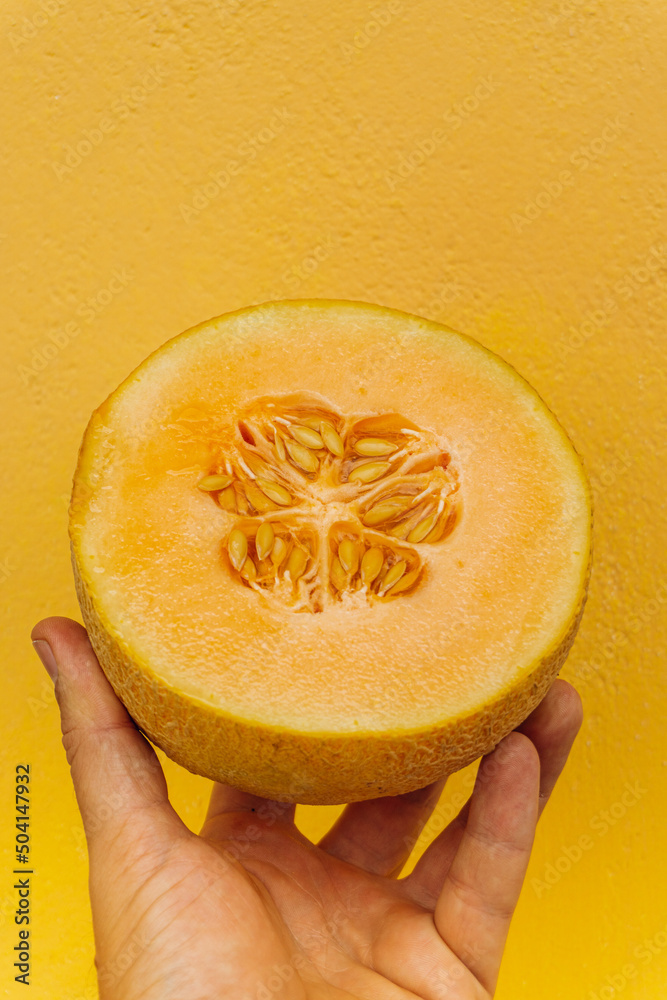 Melon kantalupa, tropikalny owoc na żółtym tle.