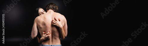 Passionate woman scratching back of muscular man on black background, banner.