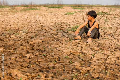 Boy in dryland looking at drought landscape. The concept for climate change from global warming. 