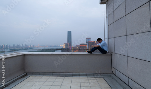 Depressed man sitting on the rooftop railing © xy