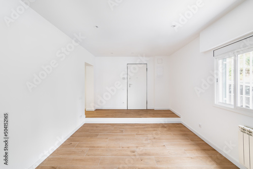 Empty room after renovation with window  white walls and wooden floor in new apartment
