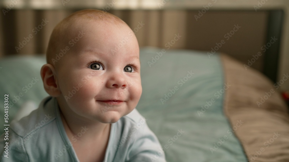 7 month old boy laughs, close up. Very cute baby smiles at mom. A very handsome newborn boy laughs funny.