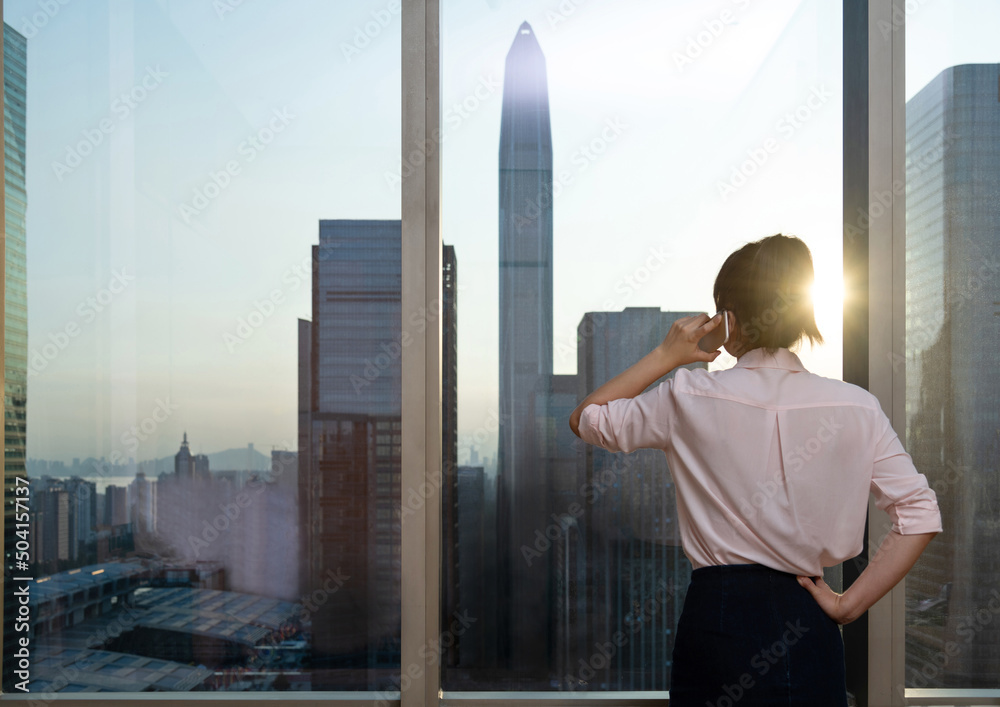 Businesswoman using mobile phone in front of the window