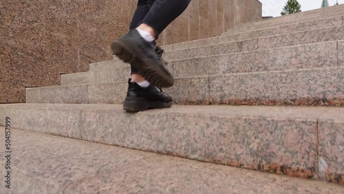 Women's feet are walking up the stone stairs in comfortable sneakers. Walking