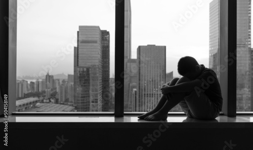 Sad boy sitting on windowsill