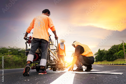Fotografija A road worker paints and observes pedestrian lines crossing the road on asphalt surface using a paint truck during a sidewalk maintenance work on the Asian Highway