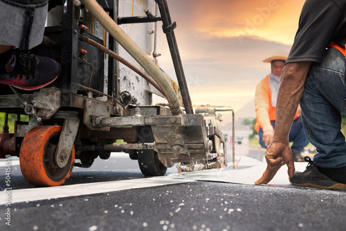 A road worker paints and observes pedestrian lines crossing the road on asphalt surface using a paint truck during a sidewalk maintenance work on the Asian Highway.