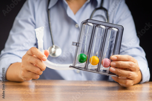 Close-up of a doctor's hands holding an incentive spirometer while sitting in the hospital photo