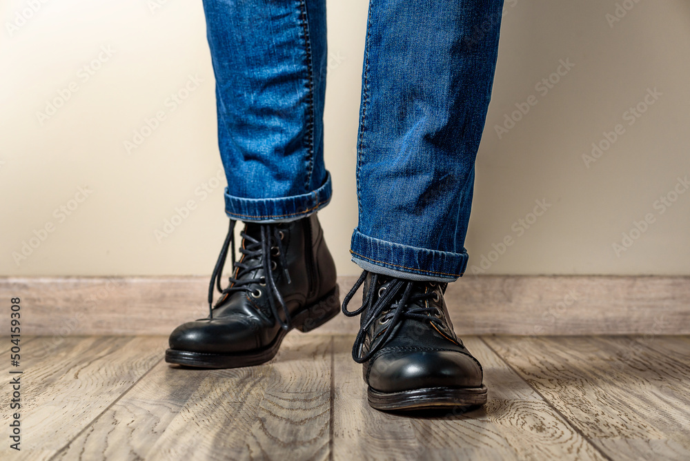 Man in black leather boots and jeans on a wooden floor Man in black leather boots and jeans on a wooden floor