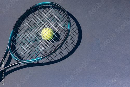 Directly above view of tennis racket on ball over gray court during sunny day