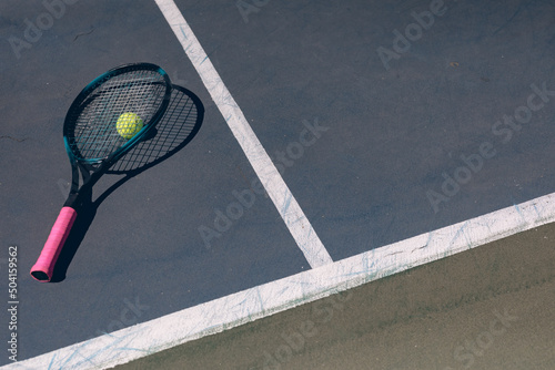 High angle view of tennis racket on ball and court with lines during sunny day