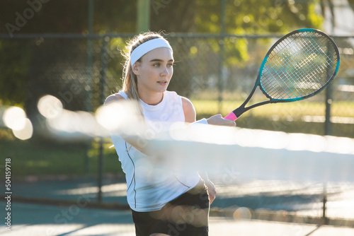 Beautiful young female caucasian athlete playing tennis with racket at court on sunny day © wavebreak3