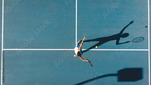 Overhead view of african american young female player serving on blue tennis court during sunny day photo