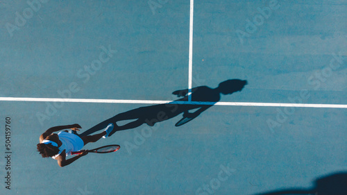 Overhead view of young african american female tennis player with shadow playing on blue court