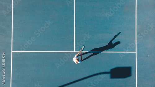 Directly above view of young caucasian female player playing on blue tennis court during sunny day